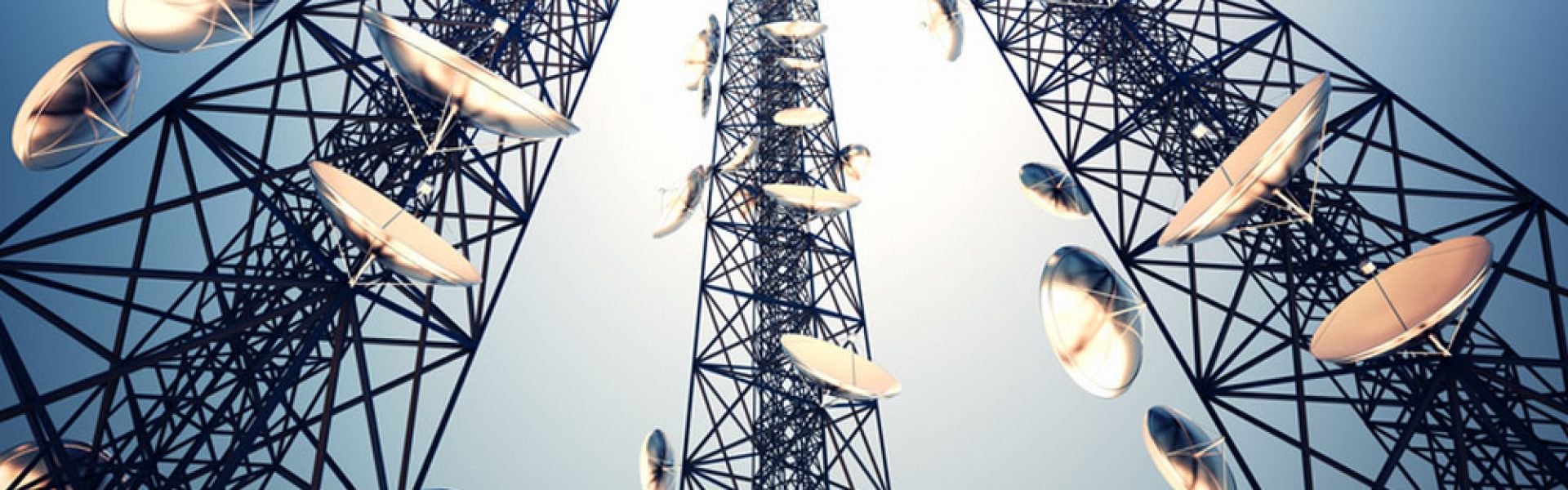 Three tall telecommunication towers with antennas on blue sky. View from the bottom.