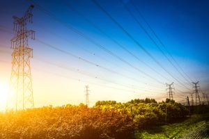 Sun setting behind the silhouette of electricity pylons