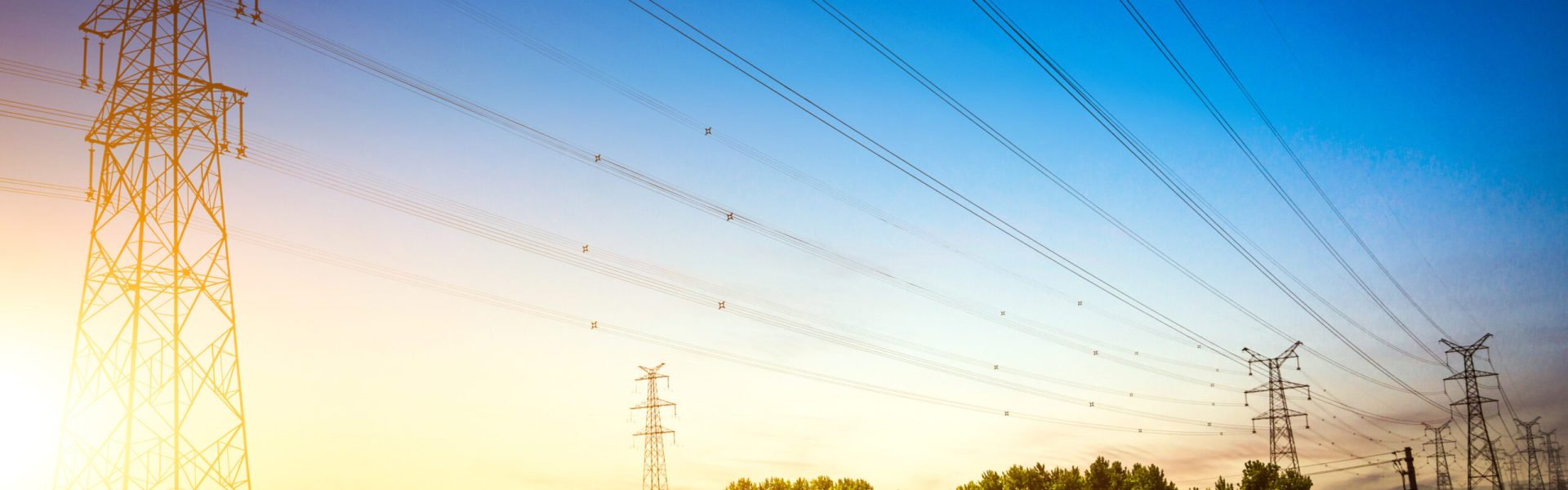 Sun setting behind the silhouette of electricity pylons