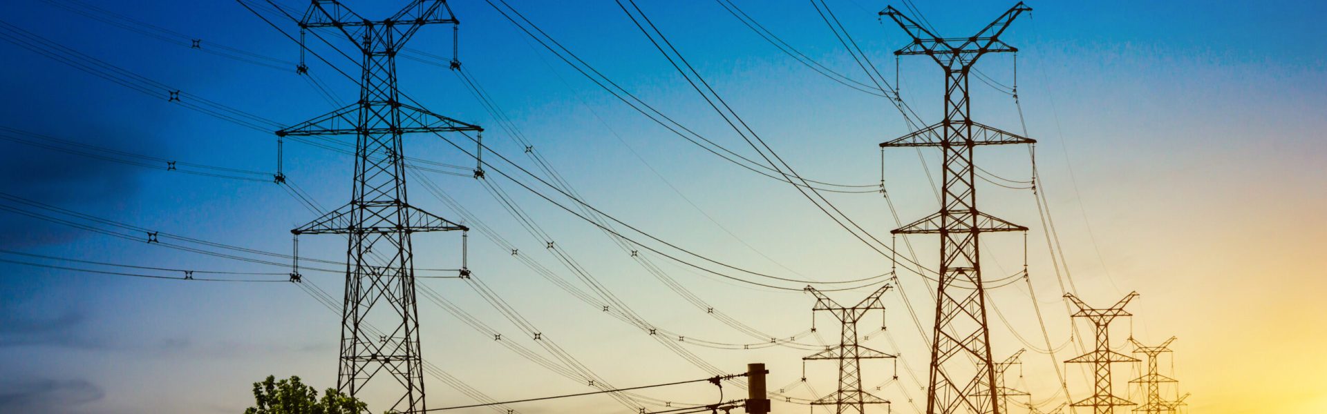 Sun setting behind the silhouette of electricity pylons